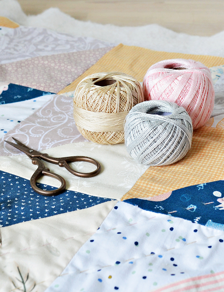 scissors and thread sitting on quilt